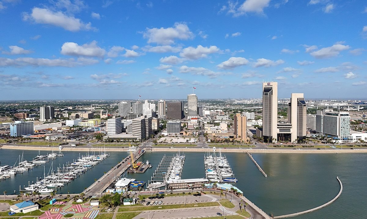 Downtown Corpus Christi seen from the air across the marina, with sailboats moored along the bayfront